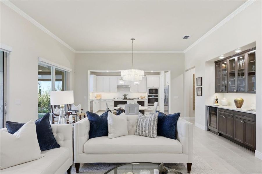 Living room featuring ornamental molding, beverage cooler, a chandelier, bar, and light tile patterned floors