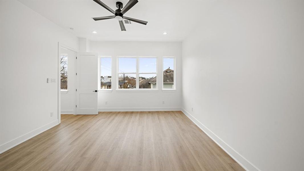 Spacious primary bedroom located on the third floor, featuring recessed lighting, a ceiling fan, and luxury vinyl plank floors.