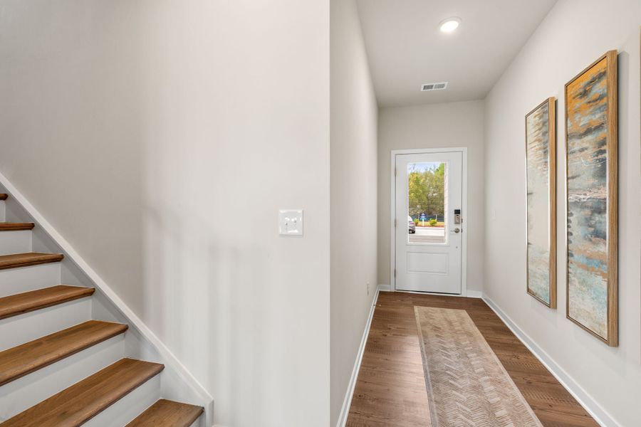 A hallway with a door and a staircase. A hallway with a door and a staircase.