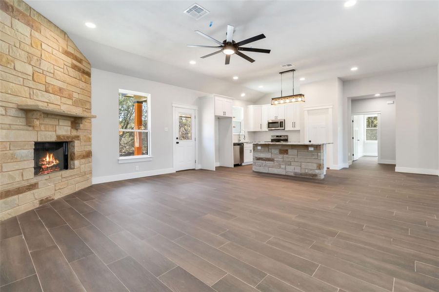 living room featuring ceiling fan, a fireplace, and vaulted ceiling