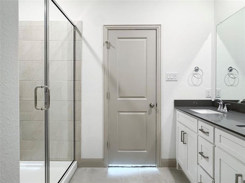 Full bathroom featuring vanity, a shower stall, and baseboards