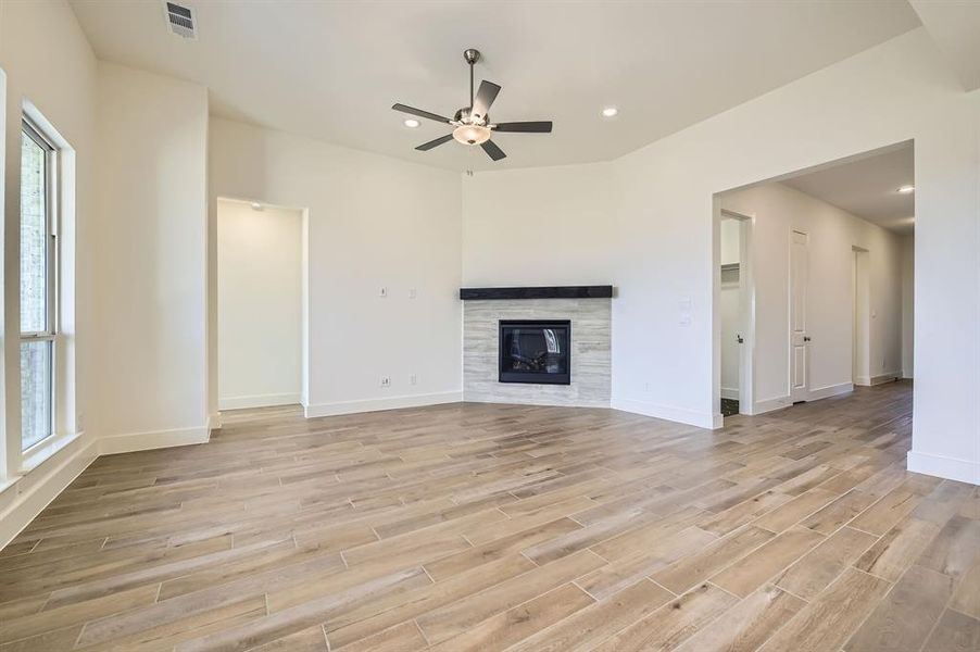 Unfurnished living room with baseboards, recessed lighting, ceiling fan, light wood-style floors, and a tiled fireplace