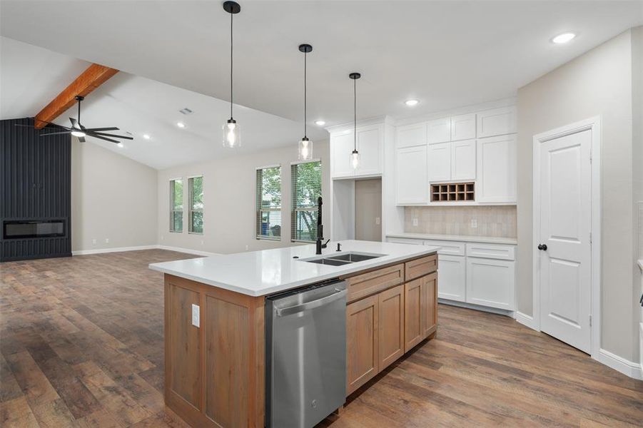 Kitchen featuring dishwasher, open floor plan, white cabinetry, dark wood finished floors, and decorative light fixtures