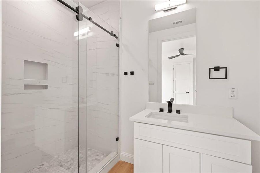 Bathroom featuring a marble finish shower, vanity, and light wood-style floors Bathroom featuring a marble finish shower, vanity, and light wood-style floors
