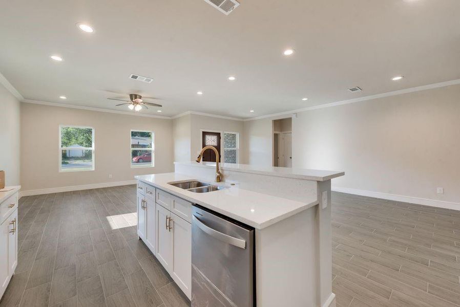 Kitchen with dishwasher, ceiling fan, a kitchen island with sink, white cabinetry, and sink