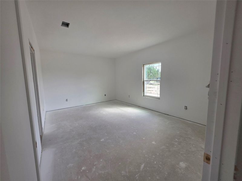 Spacious room with white walls and a single window, featuring a ceiling vent and visible electrical outlets