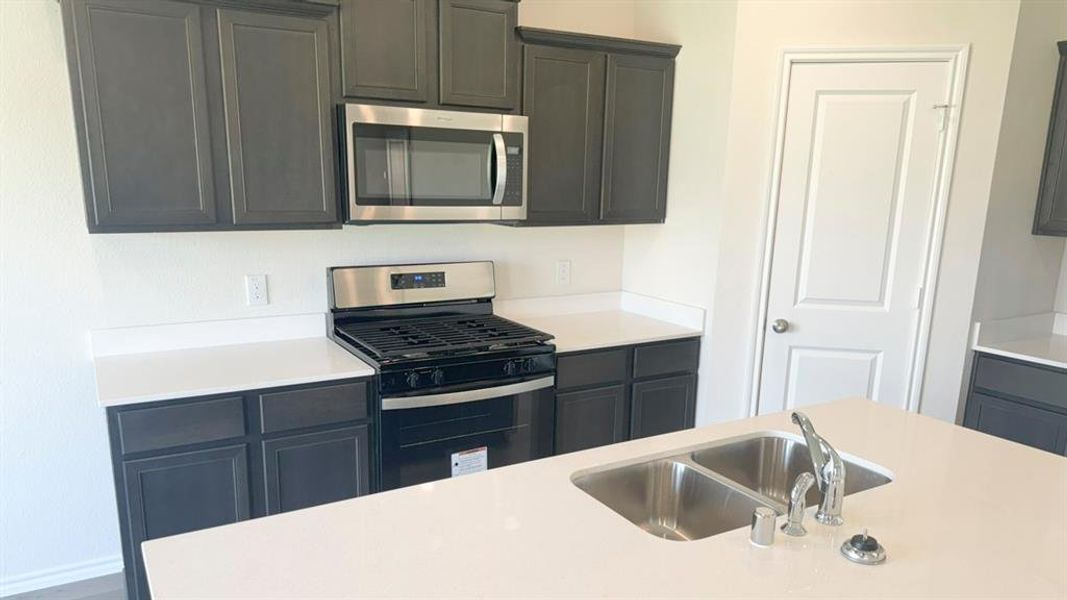 Kitchen with appliances with stainless steel finishes and light stone countertops
