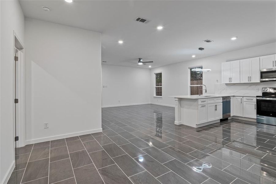 Kitchen featuring white cabinetry, stainless steel appliances, kitchen peninsula, and pendant lighting