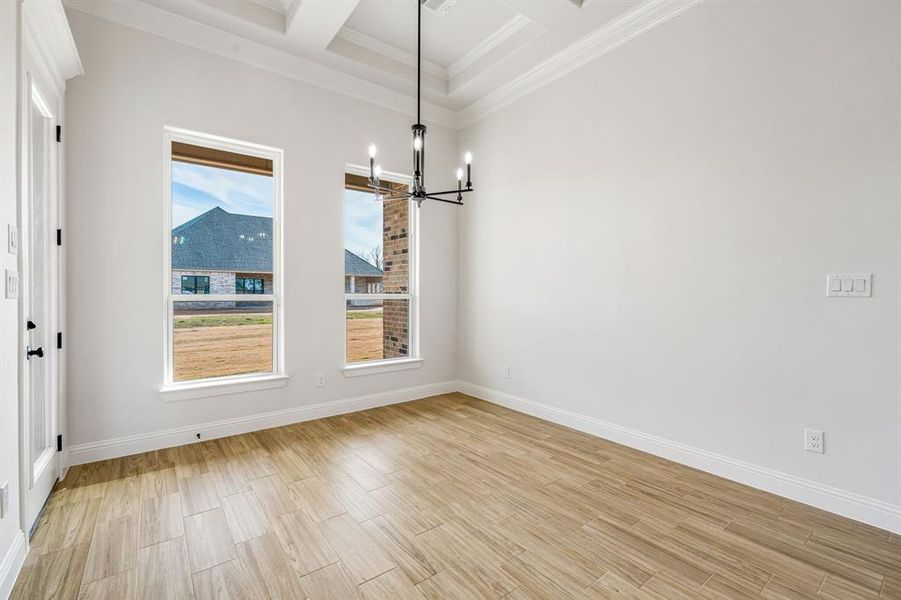 Unfurnished dining area featuring beam ceiling, ornamental molding, a chandelier, and coffered ceiling