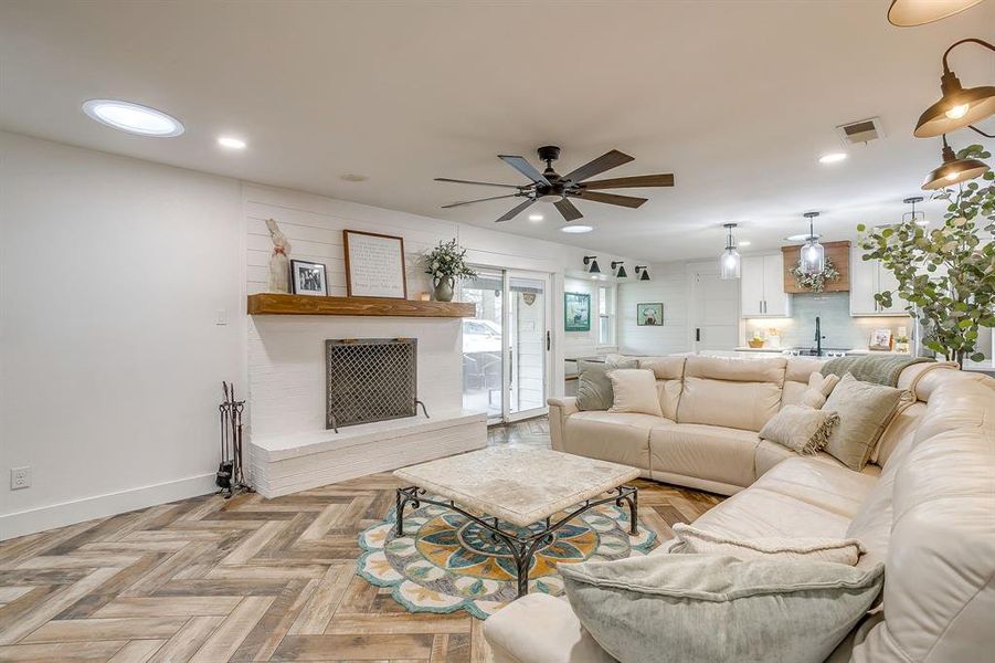 Living room featuring parquet flooring, ceiling fan, a fireplace, and recessed lighting