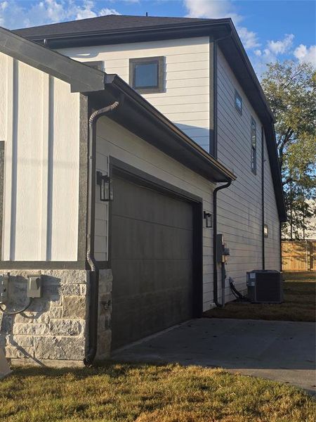 View of property exterior featuring a garage, driveway, and stone siding View of property exterior featuring a garage, driveway, and stone siding