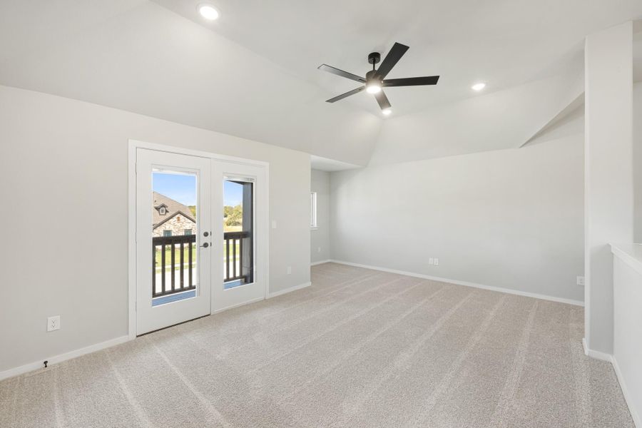 Empty room with vaulted ceiling, ceiling fan, carpet flooring, and French doors leading to a balcony