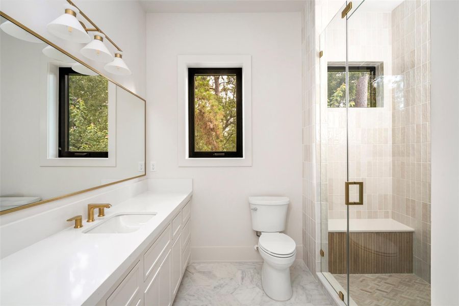 Bathroom featuring natural light, beautiful natural stone, and custom cabinetry.
