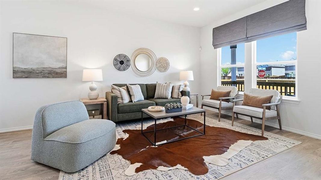 Bright living area featuring wood-finish flooring and a large window with privacy shades