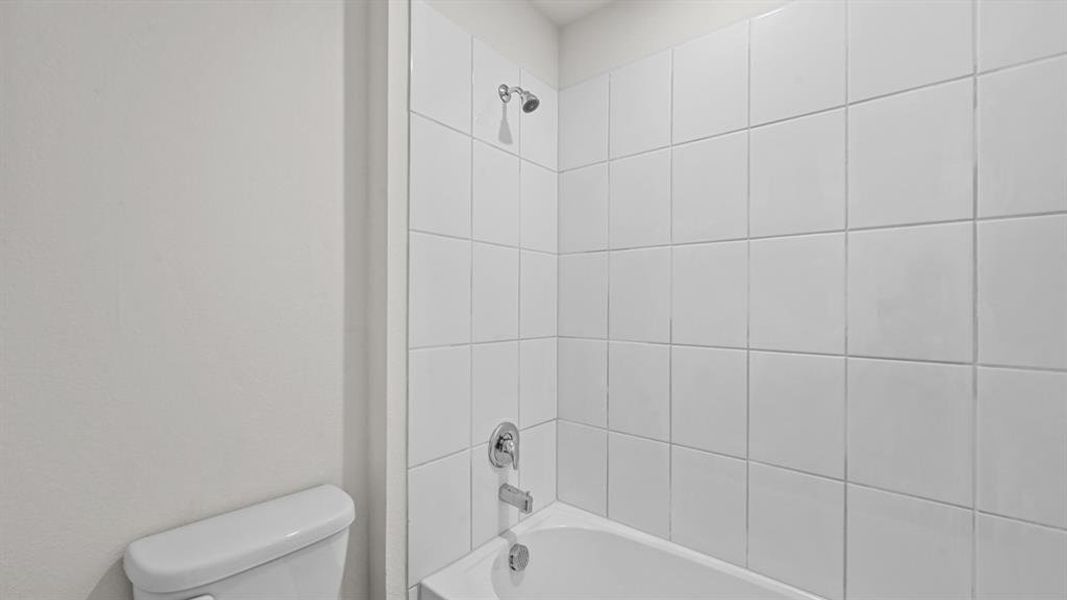 Bathtub with white subway tile surround, chrome fixtures, and a showerhead