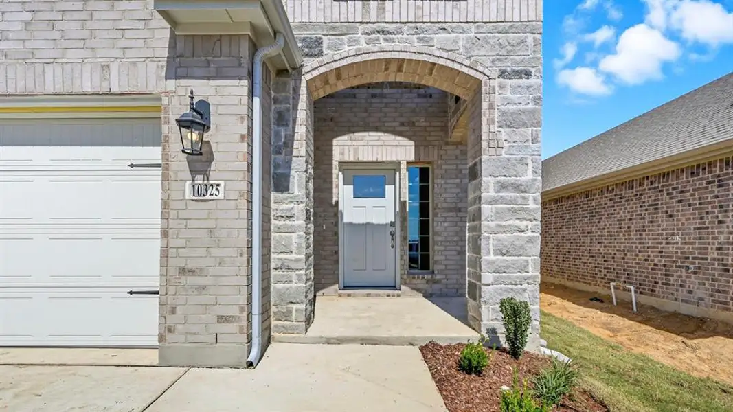 View of exterior entry featuring stone siding, a garage, and brick siding View of exterior entry featuring stone siding, a garage, and brick siding
