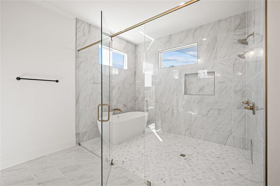 Bathroom featuring a marble finish shower and a freestanding tub