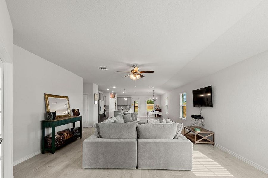Living area featuring light wood-style floors, a ceiling fan, and a chandelier