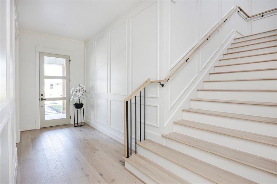 The mahogany front door is stained on the outside and painted on the inside with glass panels to allow in extra light. The entry foyer has floor to ceiling block paneling to provide dimension and character and it continues up the wide staircase to the second floor.