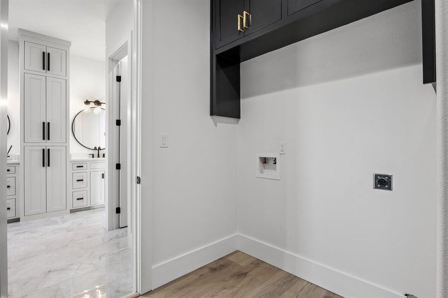 Laundry area featuring baseboards, washer hookup, light wood finished floors, cabinet space, and electric dryer hookup Laundry area featuring baseboards, washer hookup, light wood finished floors, cabinet space, and electric dryer hookup