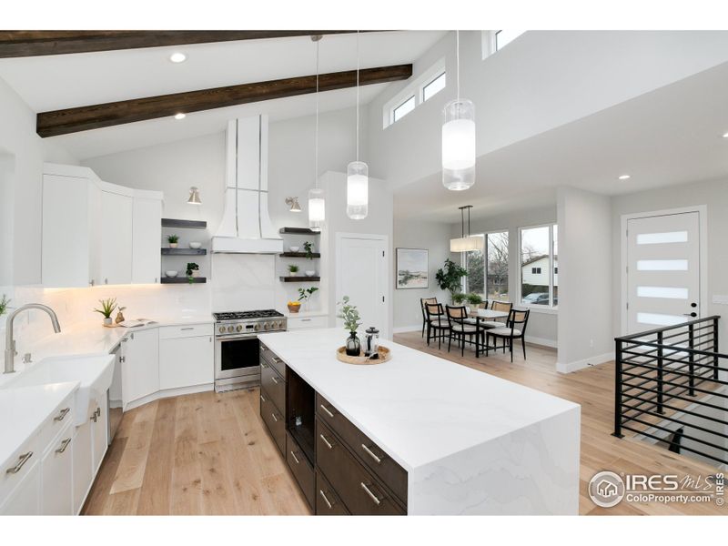 Gather friends and family in the heart of the home to enjoy the chef's kitchen with Monogram gas range, designer custom hood, custom cabinets and single slab island.