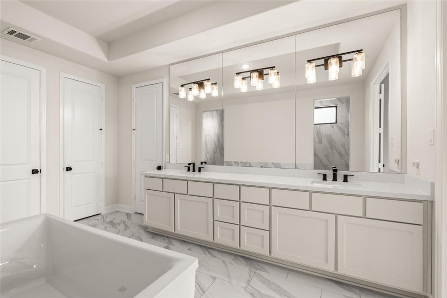 Splendid primary bathroom featuring a spacious double vanity with modern fixtures, elegant lighting, and ample cabinetry, all set against a backdrop of marble flooring.