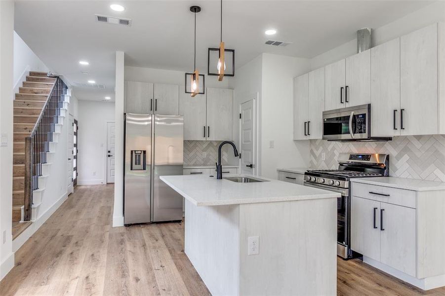 Kitchen featuring visible vents, stainless steel appliances, backsplash, and a sink