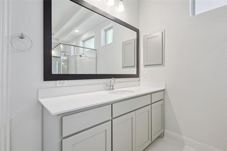 Bathroom with tile patterned flooring, a shower with shower door, and vanity