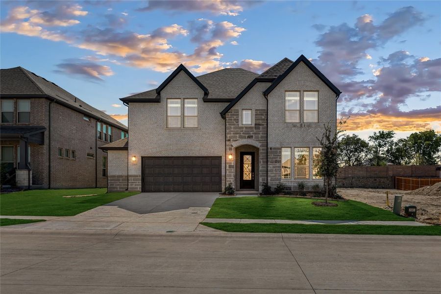 Two-story brick and stone home with two-car garage and arched front entry on a corner lot