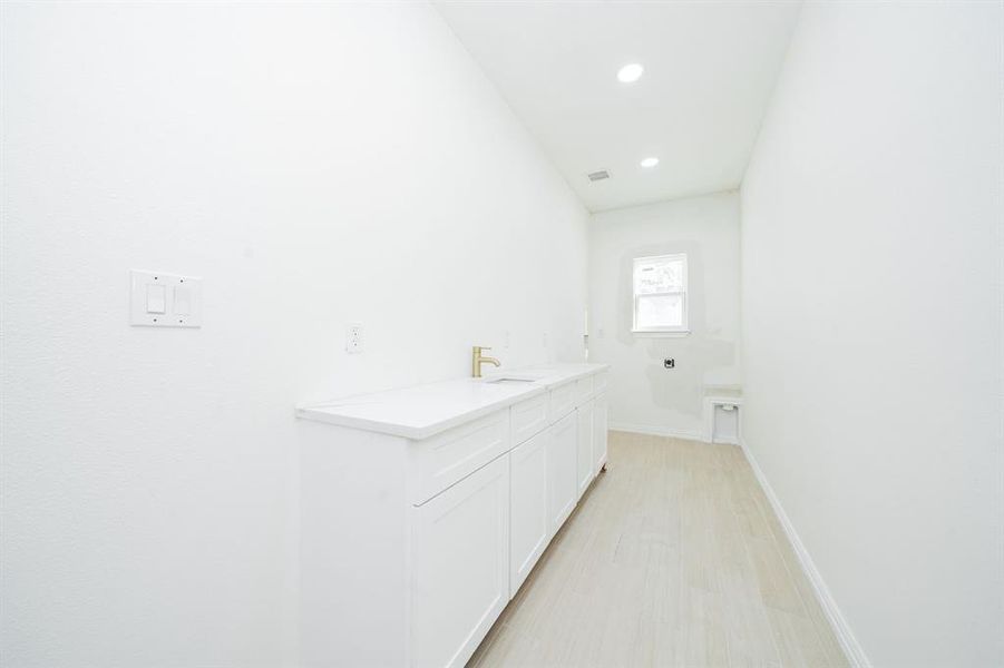 Laundry room featuring, quartz countertops, cabinets, recessed lighting, and light wood finished floors