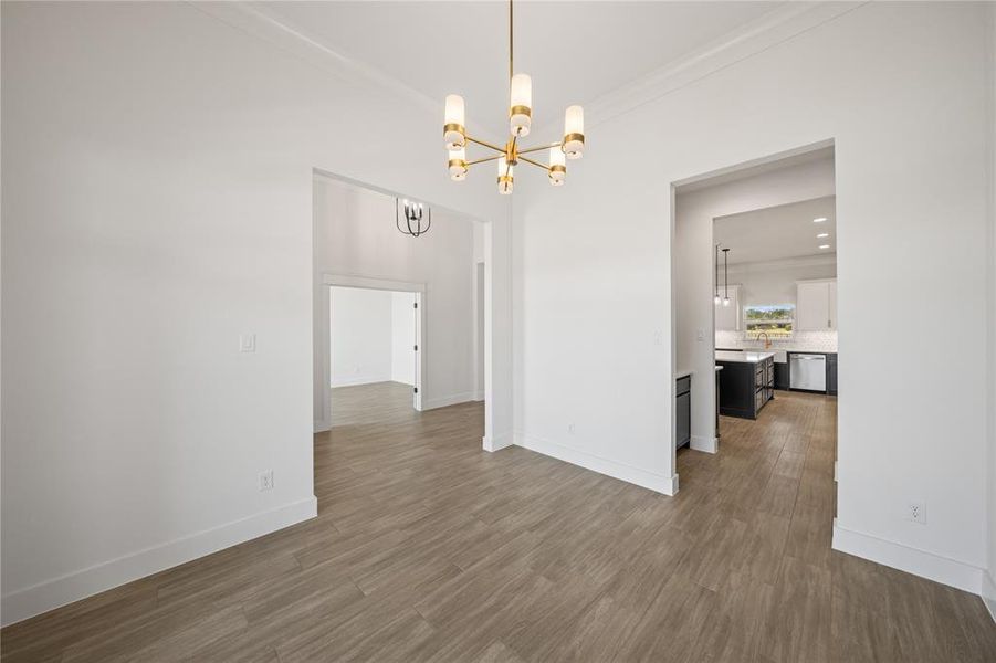Unfurnished dining area featuring ornamental molding, a chandelier, and dark wood finished floors
