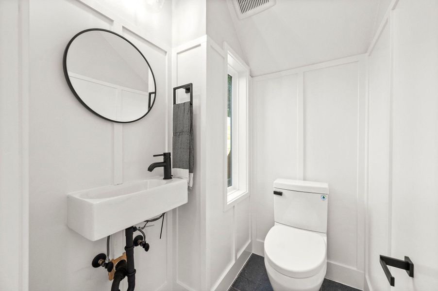 Bathroom with lofted ceiling and a decorative wall