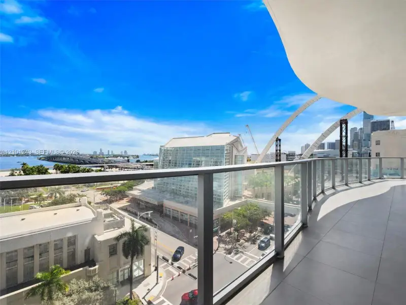 Covered balcony featuring large-format porcelain tile flooring and a glass panel railing Covered balcony featuring large-format porcelain tile flooring and a glass panel railing