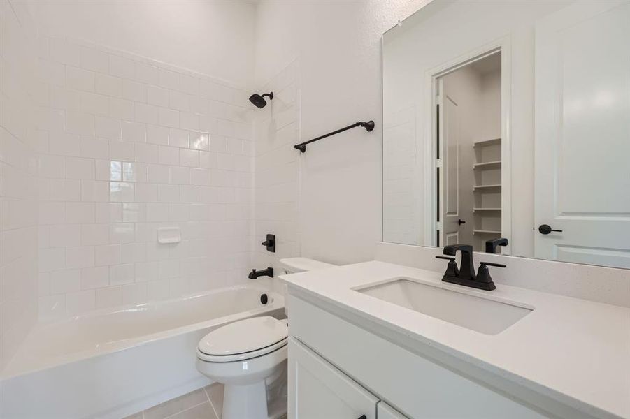 Full bathroom with tiled shower / bath, vanity, toilet, and tile patterned flooring