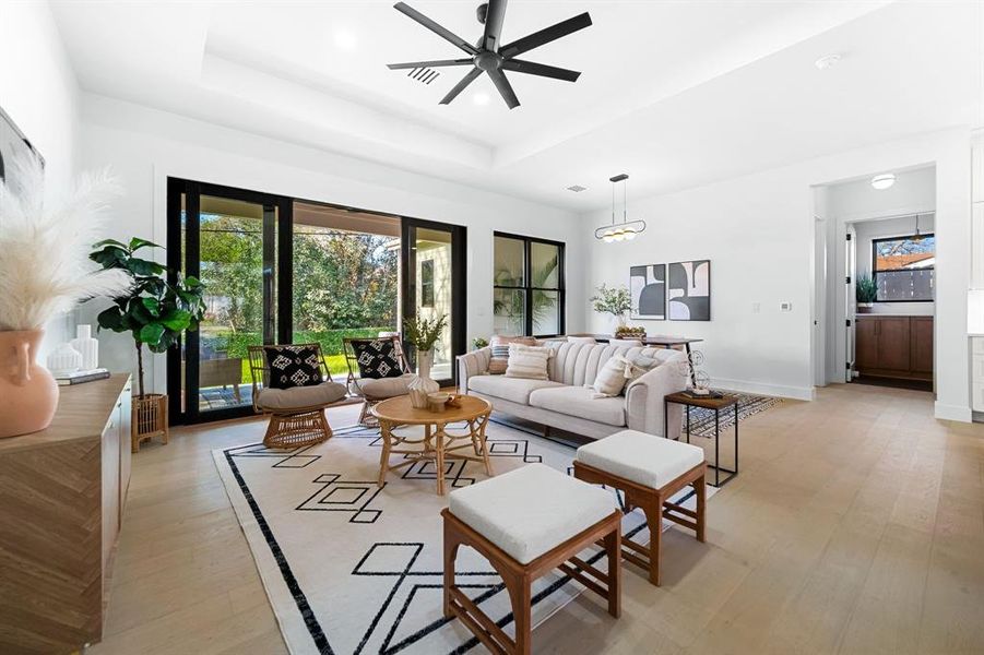 The generously sized living room is a visual delight with a tray ceiling, recessed lighting, and stackable sliding glass doors that open seamlessly to the outdoors