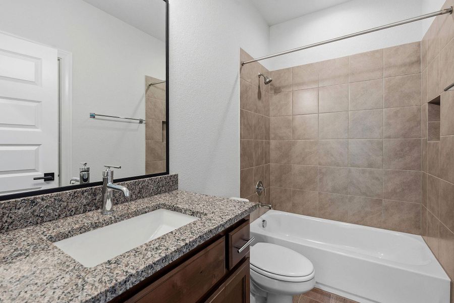 Modern bath features a granite vanity and a tub-shower combination with tile surround. Modern bath features a granite vanity and a tub-shower combination with tile surround.
