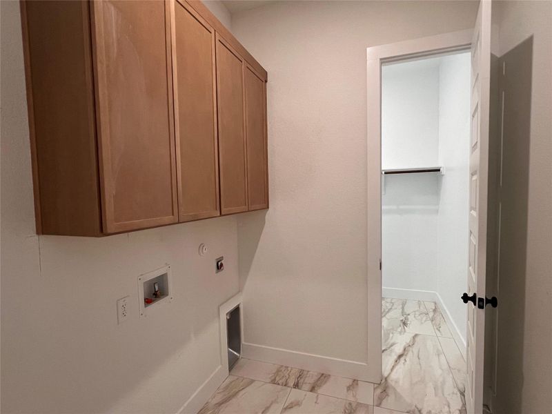 Laundry area with electric dryer hookup, washer hookup, cabinet space, and light marble finish floors