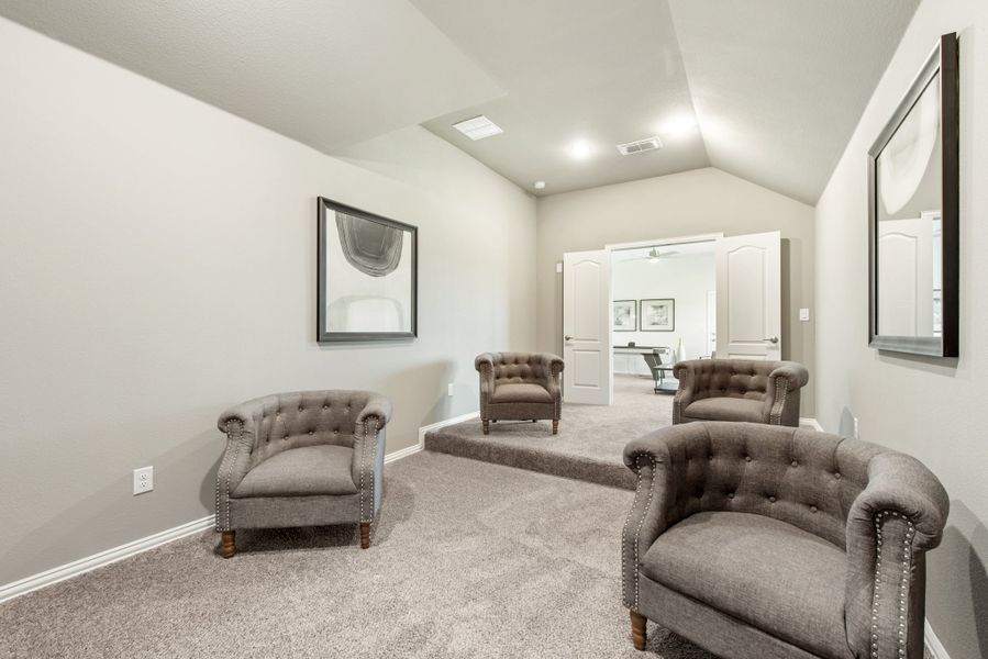 Sitting room with four tufted gray armchairs, vaulted ceiling, and neutral carpet