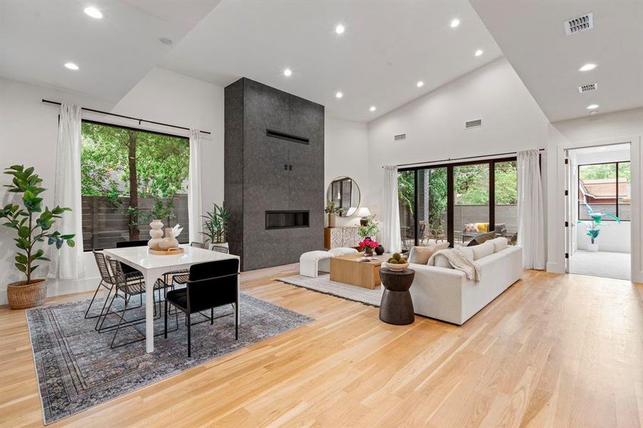 Living room featuring high vaulted ceiling, a tiled fireplace, light wood-style floors, and recessed lighting Living room featuring high vaulted ceiling, a tiled fireplace, light wood-style floors, and recessed lighting