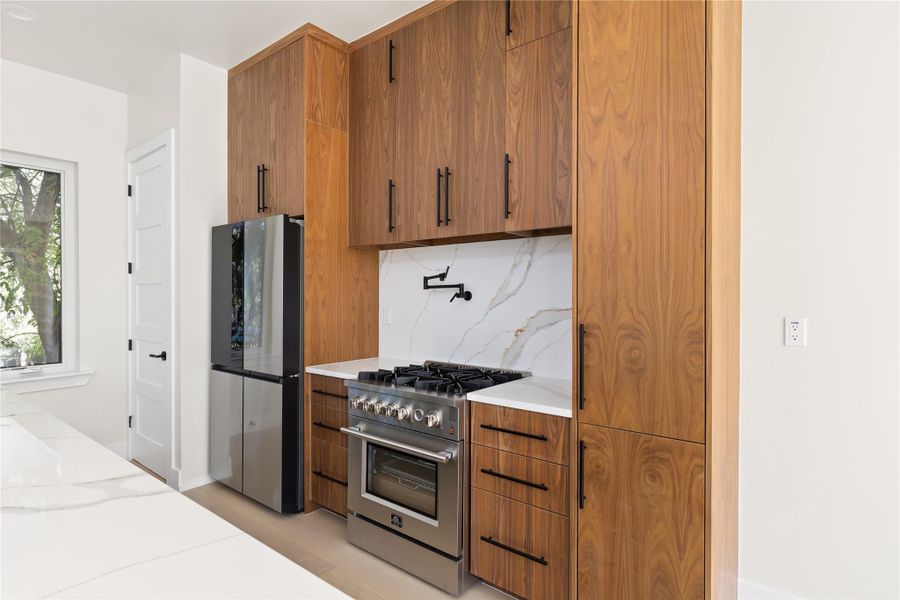 Rich wood cabinetry contrasts beautifully with white stone counters in this sleek cooking area.
