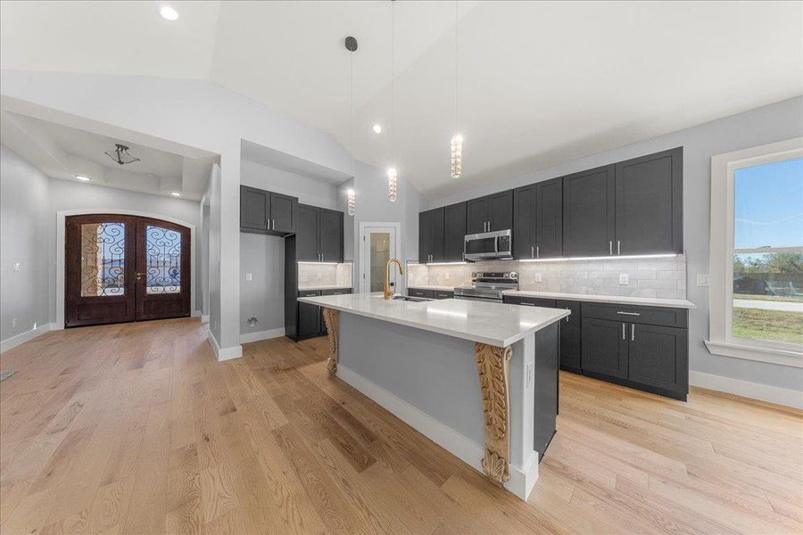 Kitchen with healthy amount of natural light, decorative light fixtures, decorative backsplash, lofted ceiling, and recessed lighting Kitchen with healthy amount of natural light, decorative light fixtures, decorative backsplash, lofted ceiling, and recessed lighting