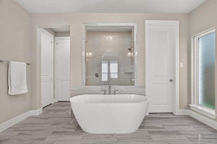 Freestanding soaking tub with a tiled shower enclosure featuring a glass surround, hexagon tile, and dual shower heads Freestanding soaking tub with a tiled shower enclosure featuring a glass surround, hexagon tile, and dual shower heads