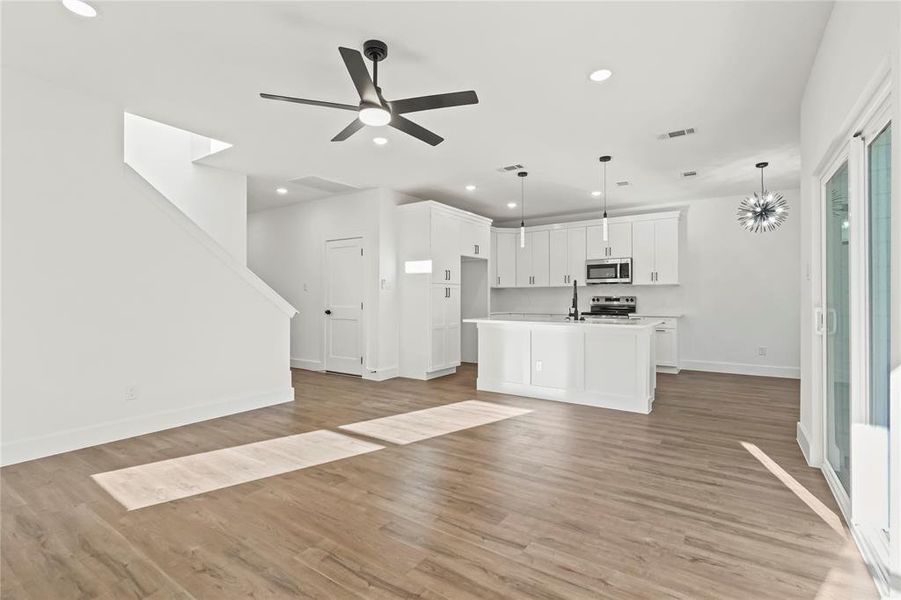 Unfurnished living room featuring light wood-type flooring, recessed lighting, a ceiling fan, and stairs