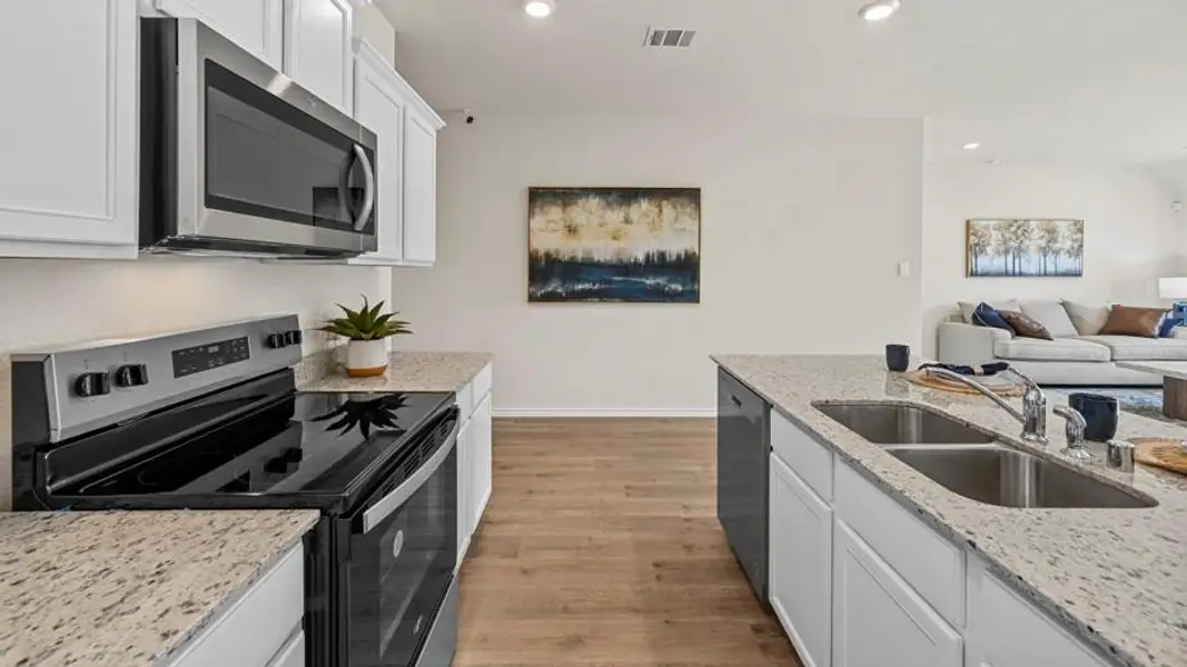 Kitchen featuring stainless steel appliances, white cabinetry, open floor plan, light stone counters, and recessed lighting