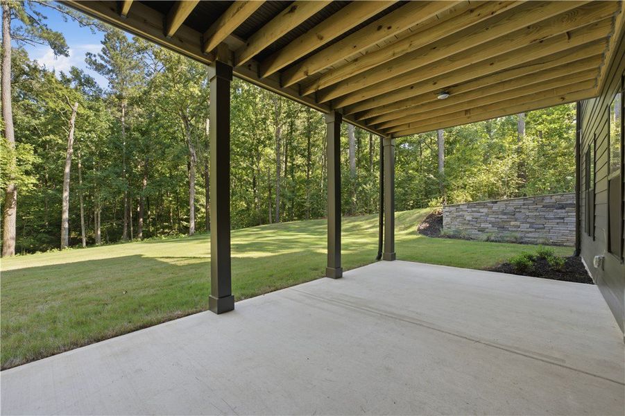 Sheltered concrete patio overlooks a grassy lawn b