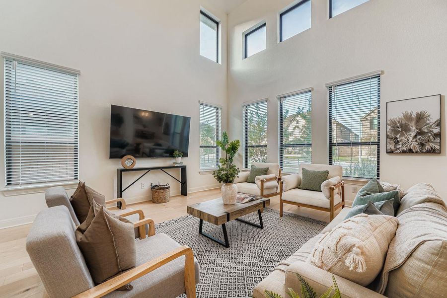 Living room featuring light wood finished floors, a high ceiling, and plenty of natural light Living room featuring light wood finished floors, a high ceiling, and plenty of natural light