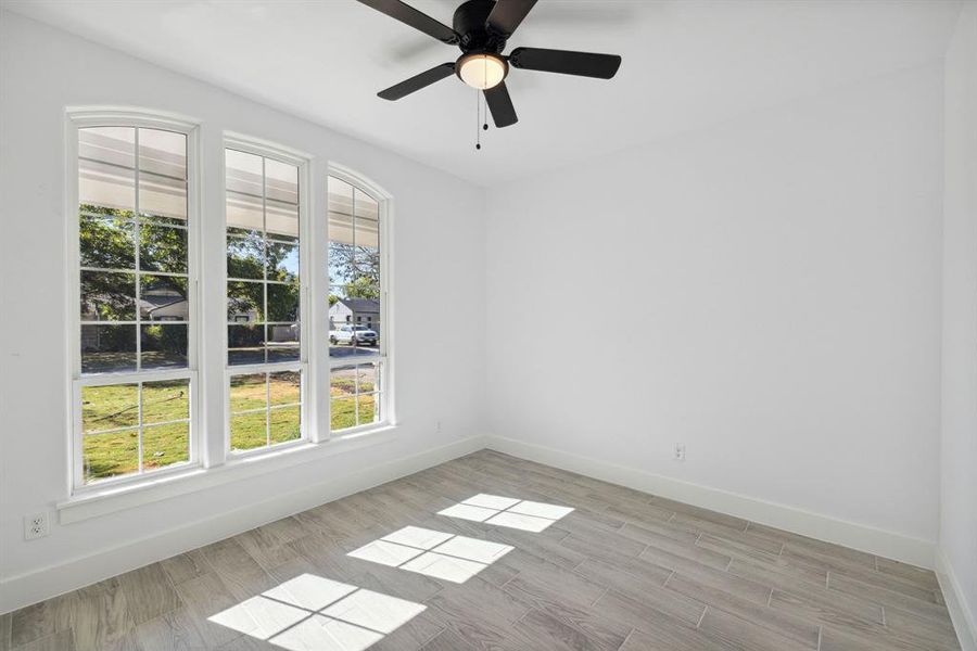 Empty room with light hardwood / wood-style floors, a healthy amount of sunlight, and ceiling fan