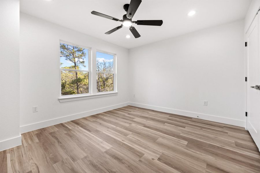Empty room with ceiling fan, light wood-type flooring, and recessed lighting