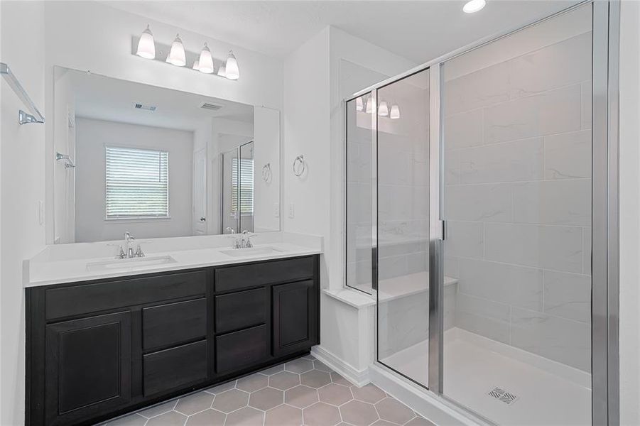 This primary bathroom is definitely move-in ready! Featuring a walk-in shower with tile surround, dark stained cabinets with light countertops, spacious walk-in closet with shelving, high ceilings, custom paint, sleek and dark modern finishes.