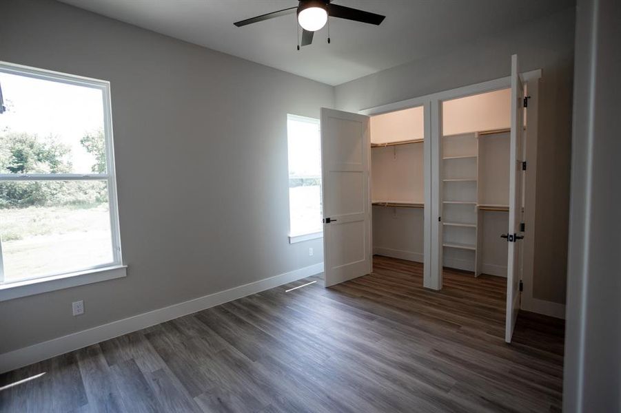 Unfurnished bedroom featuring wood finished floors, two closets, and ceiling fan Unfurnished bedroom featuring wood finished floors, two closets, and ceiling fan